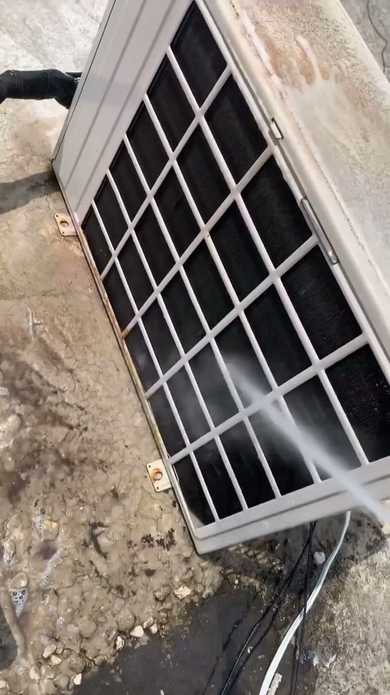 Technician washing an outdoor condenser